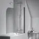 Duschsystem von Ideal Standard mit verchromtem Duschkopf und Handbrause, in einer modernen Badewanne integriert. Klare Trennwand aus Glas im minimalistischen Raum.